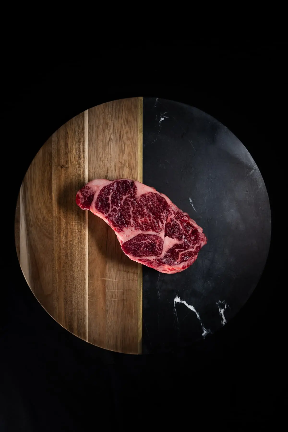 Rauwe dry-aged steak op een houten snijplank, van bovenaf.